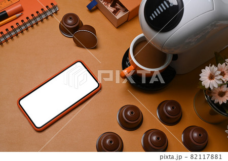Mock up smart phone, coffee machine and coffee capsules on brown leather. Mock up smart phone, coffee machine and coffee capsules on brown leather. 82117881