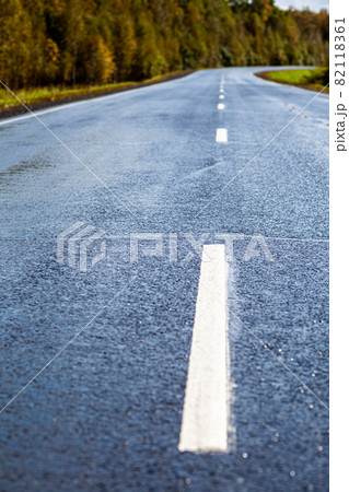 Straight road with a marking on the nature background. Open Road in future, no cars, auto on asphalt road through green forest, trees. Clouds on blue sky in summer, sunshine, sunny day. Bottom view Straight road with a marking on the nature background. Open Road in future, no cars, auto on asphalt road through green forest, trees. Clouds on blue sky in summer, sunshine, sunny day. Bottom view 82118361