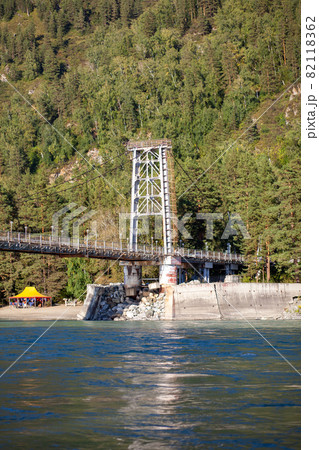 A suspension bridge over a wide river in the mountains. Safe crossing of the bridge from one bank to the other. 82118362