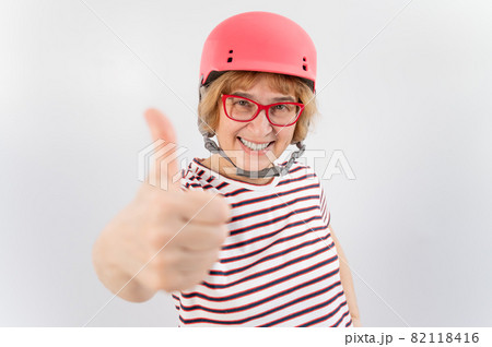 Elderly woman in ski helmet showing thumb up on white background. Elderly woman in ski helmet showing thumb up on white background. 82118416