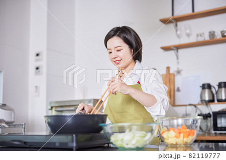 キッチンで料理をするエプロン姿の若い女性 キッチンで料理をするエプロン姿の若い女性 82119777