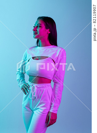 Studio portrait of young beautiful girl isolated over blue background in neon light Studio portrait of young beautiful girl isolated over blue background in neon light 82119907