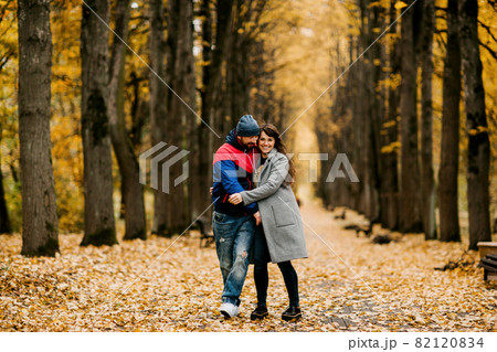 Two lovers walk along an alley in an autumn park and hug each other. Autumn, love, a romantic date Two lovers walk along an alley in an autumn park and hug each other. Autumn, love, a romantic date 82120834