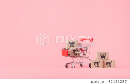 Shopping concept : Cartons or Paper boxes in red shopping cart on pink background. online shopping consumers can shop from home and delivery service. with copy space Shopping concept : Cartons or Paper boxes in red shopping cart on pink background. online shopping consumers can shop from home and delivery service. with copy space 82121227