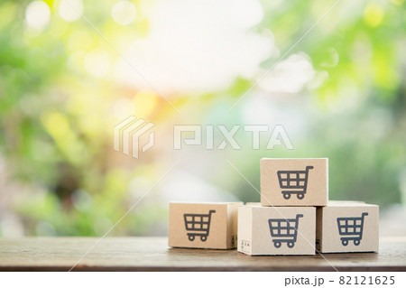 Online shopping - Paper cartons or parcel with a shopping cart logo and credit on wood table top with copy space. Shopping service on The online web and offers home delivery. 82121625