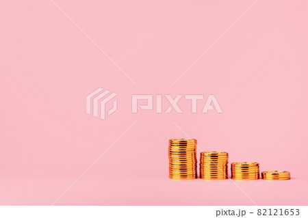 Money saving and investment concept. Wooden houses standing on stacks of coins. on pink background with copy space 82121653