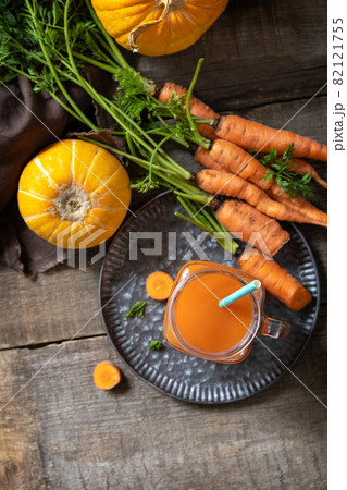 Fresh natural mixed juice, healthy food concept. Glass jar of fresh carrot juice with fresh carrots and pumpkin on a wooden rustic table. Top view flat lay background. Fresh natural mixed juice, healthy food concept. Glass jar of fresh carrot juice with fresh carrots and pumpkin on a wooden rustic table. Top view flat lay background. 82121755