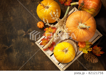 Concept of Halloween or Thanksgiving day, autumn harvest. Festive autumn seasonal decorations with pumpkins and leaves on a rustic wooden background. Top view flat lay background. Copy space. 82121756