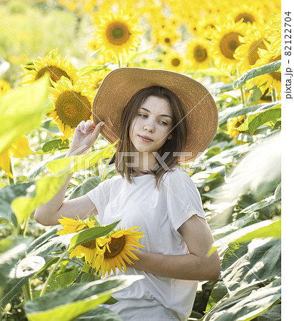 Young beautiful girl walking in the field with sunflowers 82122704