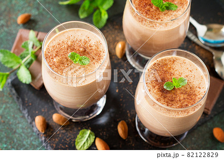 Chocolate-nut mousse close-up with mint in portion glasses on a stone or slate background. Chocolate-nut mousse close-up with mint in portion glasses on a stone or slate background. 82122829