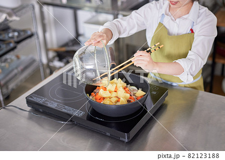 キッチンでカレーを作るエプロン姿の若い女性 キッチンでカレーを作るエプロン姿の若い女性 82123188