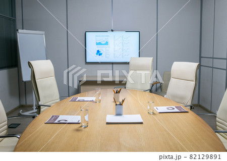 Armchairs around large table with papers, glasses and pens 82129891