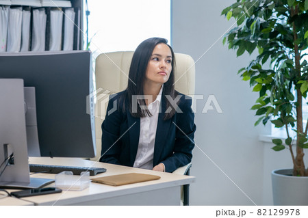 Young contemporary businesswoman sitting by workplace 82129978