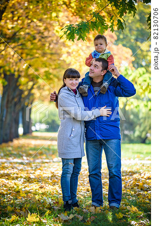 Family of three walks in the autumn park holding hands. happy father carrying son with maple leaves. Mother embrace her cute boy child. Happy family leisure together concept Family of three walks in the autumn park holding hands. happy father carrying son with maple leaves. Mother embrace her cute boy child. Happy family leisure together concept 82130706