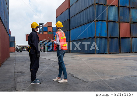 Industrial worker works with co-worker at overseas shipping container yard 82131257