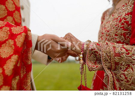 hindu bride walks behind husband holding garb 82131258