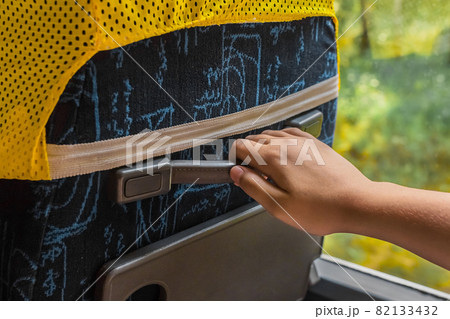 The girl's hand is holding on to the rubber handle of the seat on the bus, close-up The girl's hand is holding on to the rubber handle of the seat on the bus, close-up 82133432