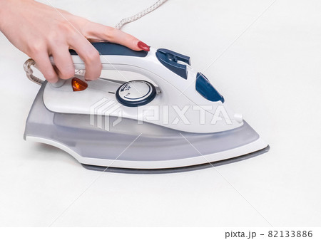 Girl's hand ironing a white tablecloth background Girl's hand ironing a white tablecloth background 82133886