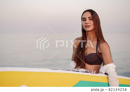 Young woman is carrying paddle board at the beach 82134258