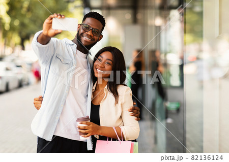 Happy black couple taking selfie after shopping at mall 82136124