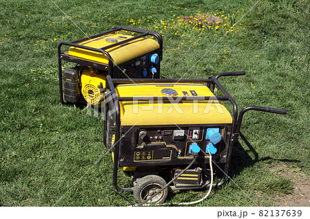 Autonomous portable yellow diesel generator stands on the grass 82137639