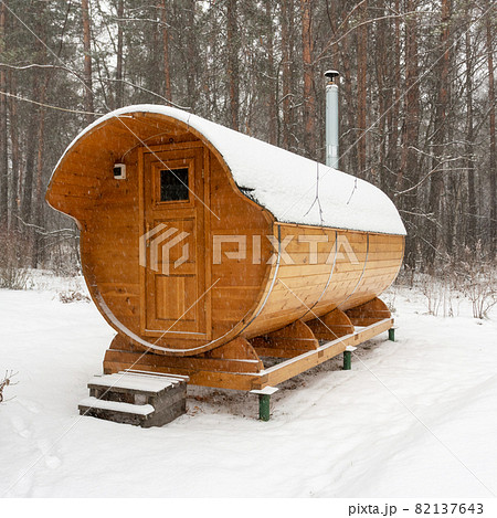 Bath barrel on a background of a winter forest. The first fluffy snow is falling. Health care 82137643