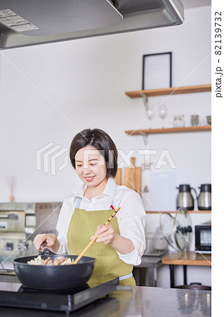 キッチンで料理をするエプロン姿の若い女性 82139732