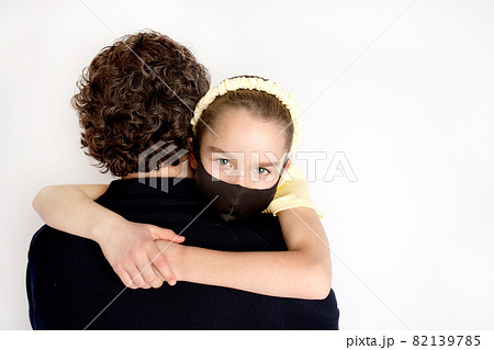 A girl in a black antibacterial mask and a yellow T-shirt in her father's arms. A girl in a black antibacterial mask and a yellow T-shirt in her father's arms. 82139785