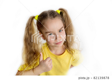 Little blonde girl in a yellow t-shirt makes gestures, raising her fingers, isolated on a white background. Childhood lifestyle concept 82139878