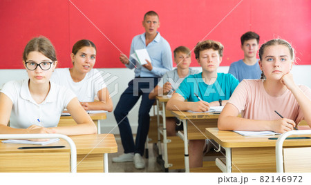 Teenagers listening to lecturer and writing in notebooks in classroom Teenagers listening to lecturer and writing in notebooks in classroom 82146972