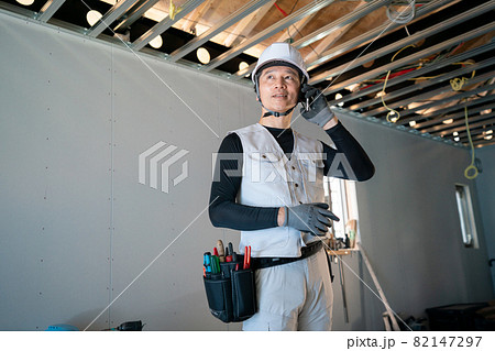 建築現場でスマホで話をする職人 82147297