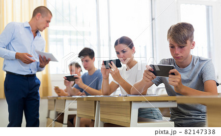 Pupils with smartphones sitting in class 82147338
