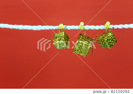 Gold gift box hang on the clothesline and have copy space with red background. Gold gift box hang on the clothesline and have copy space with red background. 82150292