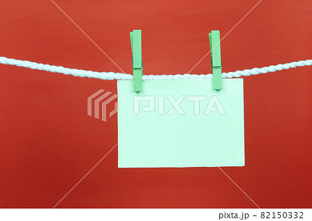Empty note green paper hang on the clothesline and have copy space with red background. Empty note green paper hang on the clothesline and have copy space with red background. 82150332