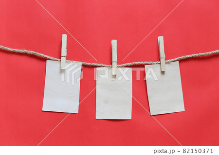Blank brown note on clothesline and red background. 82150371