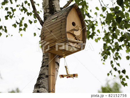 A beautiful wooden birdhouse hangs on a birch tree in summer, close-up. Copy space for text, handmade A beautiful wooden birdhouse hangs on a birch tree in summer, close-up. Copy space for text, handmade 82152756