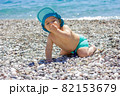 Sweet chubby baby on a pebble beach. Blue sea and summer sunshine 82153679