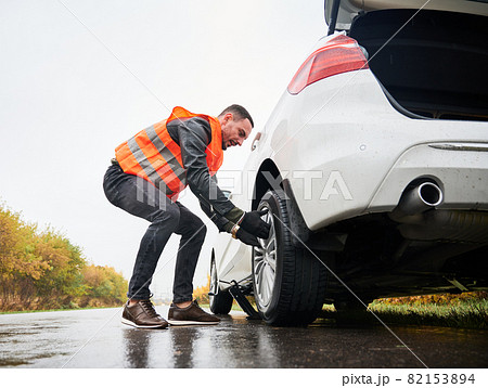 Roadside assistance worker removing flat tire. 82153894 PIXTA