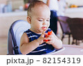 Sweet baby boy eating red watermelon sitting at baby chair in restaurant. Hotel vacation with child 82154319