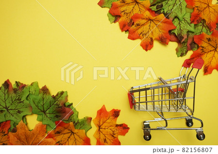 Shopping trolley over Yellow Background with yellow autumn leaves border Shopping trolley over Yellow Background with yellow autumn leaves border 82156807