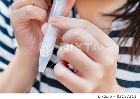 PCR検査キットを使用し、自宅で唾液を採取する女性の写真。PCR検査のイメージ。 PCR検査キットを使用し、自宅で唾液を採取する女性の写真。PCR検査のイメージ。 82157213