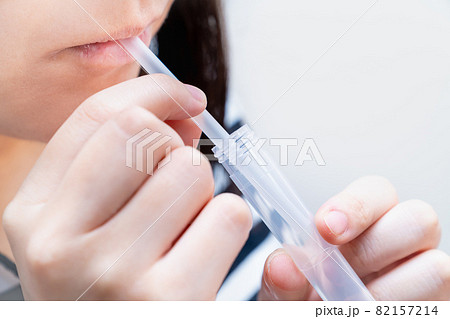PCR検査キットを使用し、自宅で唾液を採取する女性の写真。PCR検査のイメージ。 82157214