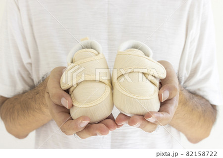 赤ちゃん用の靴を持った男性の手 82158722