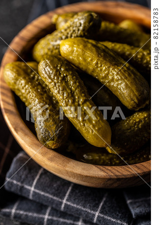 Small pickles. Marinated pickled cucumbers in wooden bowl. 82158783