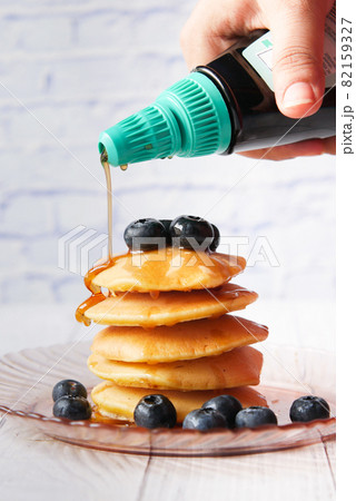 pouring maple syrup on pancakes with fresh berries on plate pouring maple syrup on pancakes with fresh berries on plate 82159327