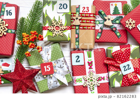 Handmade wrapped red, green gift boxes decorated with ribbons, snowflakes and numbers, Christmas decorations and decor on white table Xmas advent calendar concept Top view Flat lay Holiday card 82162283