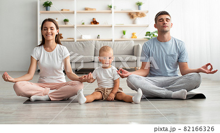 Happy Family Of Three With Little Infant Baby Meditating Together At Home Happy Family Of Three With Little Infant Baby Meditating Together At Home 82166326