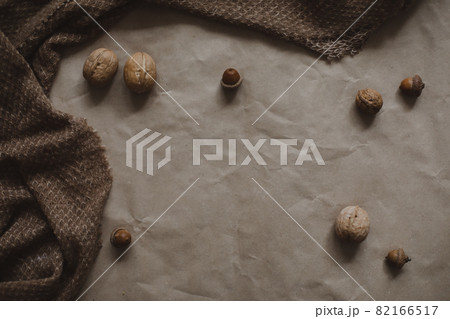 autumn theme, brown paper texture background with cozy warm plaid, walnuts and acorns, top view, copyspace 82166517