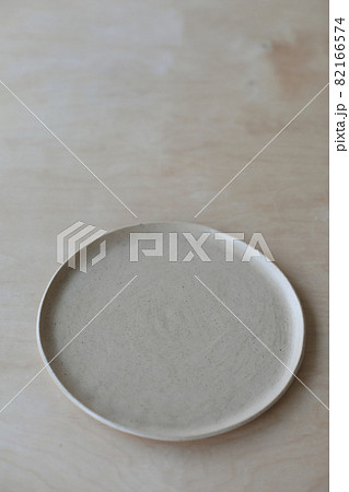 Ceramic plate on a wooden table top view. minimalist handmade ceramic tableware and pottery Ceramic plate on a wooden table top view. minimalist handmade ceramic tableware and pottery 82166574