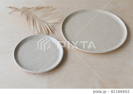 Ceramic plate on a wooden table top view. minimalist handmade ceramic tableware and pottery Ceramic plate on a wooden table top view. minimalist handmade ceramic tableware and pottery 82166602